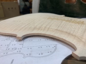 Carved maple back plate resting on an instrument graduation plan