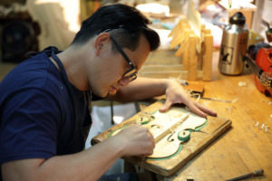 Luthier hand-carving a violin plate at the David Lien Taiwan Workshop